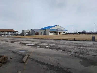 an empty parking lot with a building in the background at Millbury Motel in Millbury