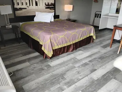 a bedroom with a bed and a wooden floor at Millbury Motel in Millbury