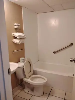 a bathroom with a toilet and a tub and a sink at Millbury Motel in Millbury