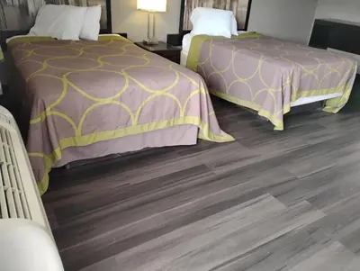 two beds in a room with wood floors at Millbury Motel in Millbury