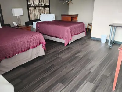 a hotel room with two beds and wooden floors at Millbury Motel in Millbury