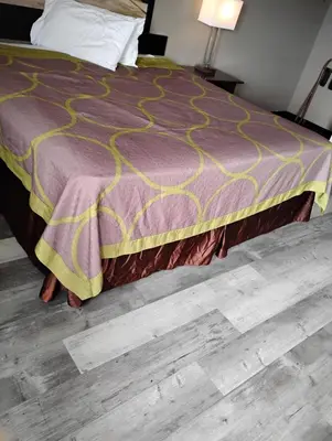 a bed with a purple comforter on top of it at Millbury Motel in Millbury