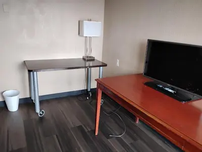 a room with a desk with a television and a table with a lamp at Millbury Motel in Millbury