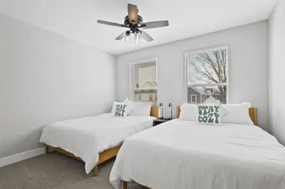 two beds in a white room with a ceiling fan at 293 Perfect for companies in Columbus