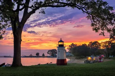a lighthouse on the shore of a lake at sunset at Vintage, Mid-Century Suite above Antique Store in Wakeman