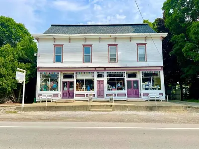 a white house with purple doors on a street at Spacious King Bed Suite at Antique Store in Wakeman