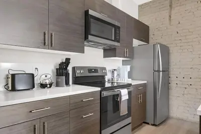 a kitchen with stainless steel appliances and wooden cabinets at Soiree Vibes Bricks & Balcony 2Bx2B DT Cleveland in Cleveland