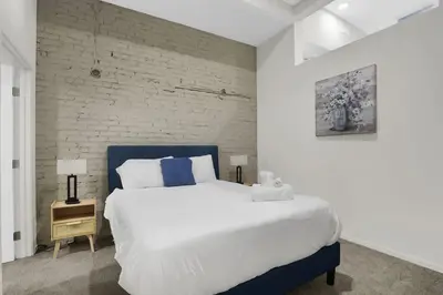 a bedroom with a large white bed and a brick wall at Soiree Vibes Bricks & Balcony 2Bx2B DT Cleveland in Cleveland