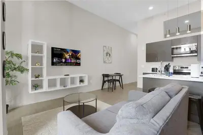 a white living room with a couch and a kitchen at Soiree Vibes Bricks & Balcony 2Bx2B DT Cleveland in Cleveland