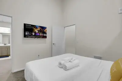 a bedroom with a white bed with a tv on the wall at Billiards & Balcony 2Bx2B Rooftop It's Lit in Cleveland