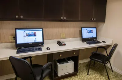 two computers sitting on a desk with two chairs at Hampton Inn & Suites New Albany Columbus in New Albany