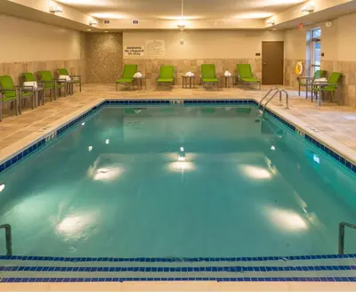 a pool in a hotel room with chairs and tables at Hampton Inn & Suites New Albany Columbus in New Albany