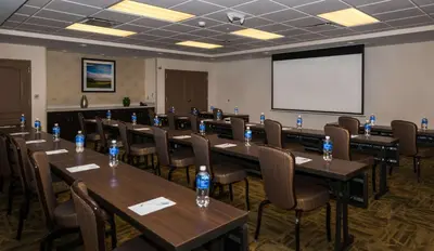 a conference room with tables and chairs and a white screen at Hampton Inn & Suites New Albany Columbus in New Albany