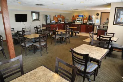 a restaurant with tables and chairs and a kitchen at Wingate by Wyndham Ashland in Ashland
