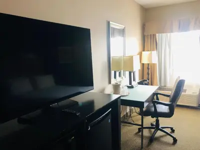 a hotel room with a desk and a large television at Wingate by Wyndham Ashland in Ashland