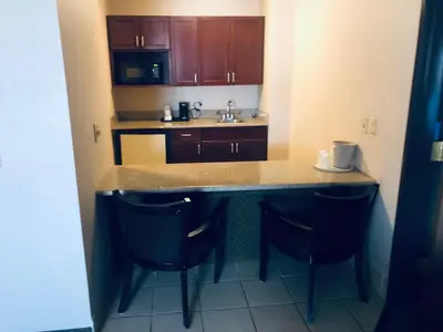 a small kitchen with a counter and two chairs at Wingate by Wyndham Ashland in Ashland