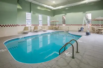 a pool in a large room with chairs and tables at Holiday Inn Express Cleveland Airport - Brook Park by IHG in Brook Park