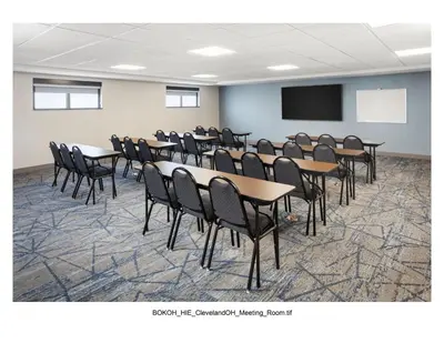 a conference room with tables and chairs and a screen at Holiday Inn Express Cleveland Airport - Brook Park by IHG in Brook Park