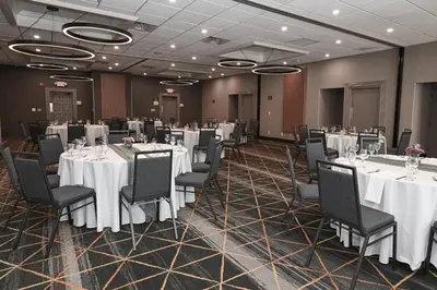a banquet room with white tables and black chairs at Holiday Inn Cleveland-Mayfield by IHG in Mayfield