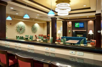 a restaurant with a waiting area with tables and chairs at Holiday Inn Express & Suites Dayton South - I-675 by IHG in Shanersville