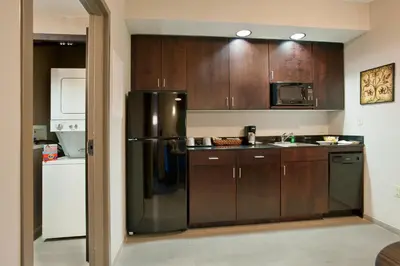 a kitchen with wooden cabinets and a stainless steel refrigerator at Holiday Inn Express & Suites Dayton South - I-675 by IHG in Shanersville
