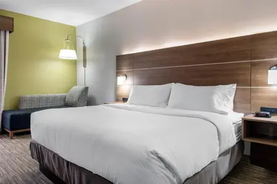 a hotel room with a large bed and a chair at Holiday Inn Express & Suites Harrison by IHG in Harrison
