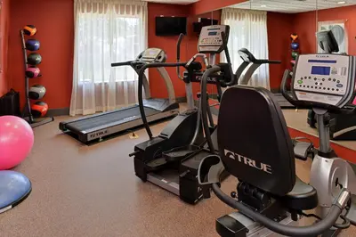 a gym with cardio equipment in a room with red walls at Holiday Inn Express & Suites Ironton by IHG in Ironton