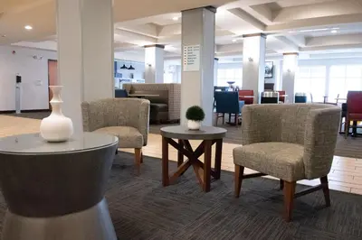 a lobby with chairs and a table with a vase on it at Holiday Inn Express & Suites Ironton by IHG in Ironton