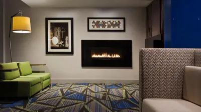 a living room with a fireplace and a green chair at Holiday Inn Express & Suites Medina by IHG in Medina