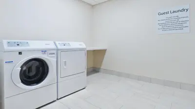 a washing machine in a white laundry room with a sign at Holiday Inn Express & Suites Medina by IHG in Medina
