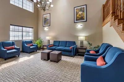 a waiting room with blue couches and a staircase at Comfort Inn & Suites Napoleon in Napoleon