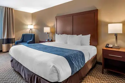 a hotel room with a large bed and a blue chair at Comfort Inn & Suites Napoleon in Napoleon