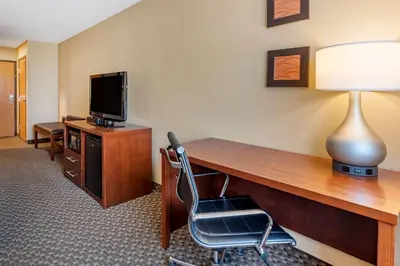 a room with a desk with a television and a chair at Comfort Inn & Suites Napoleon in Napoleon