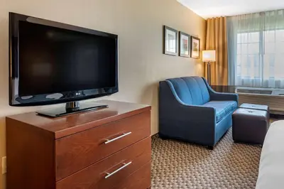 a hotel room with a flat screen tv and a chair at Comfort Inn & Suites Napoleon in Napoleon