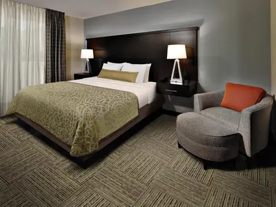 a hotel room with a bed and a chair at Staybridge Suites Toledo - Rossford - Perrysburg by IHG in Rossford