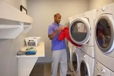 a man is putting a red towel into a washing machine at Staybridge Suites Toledo - Rossford - Perrysburg by IHG in Rossford