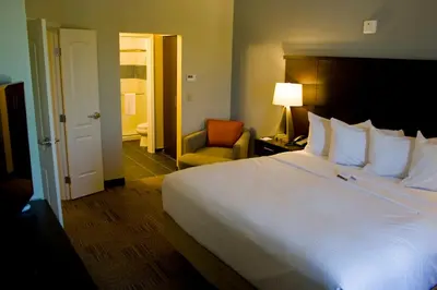 a hotel room with a large bed and a chair at Staybridge Suites Toledo - Rossford - Perrysburg by IHG in Rossford