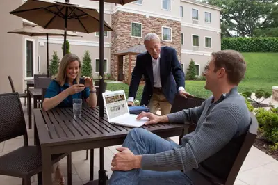 two men and a woman sitting at a table with a laptop at Staybridge Suites Toledo - Rossford - Perrysburg by IHG in Rossford