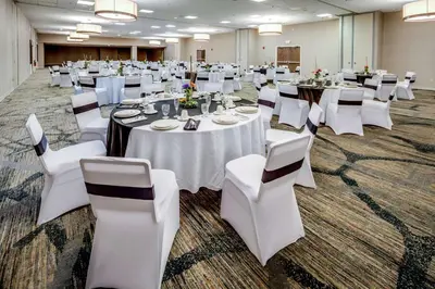 a banquet hall with white tables and white chairs at DoubleTree by Hilton Huntington, WV in Huntington