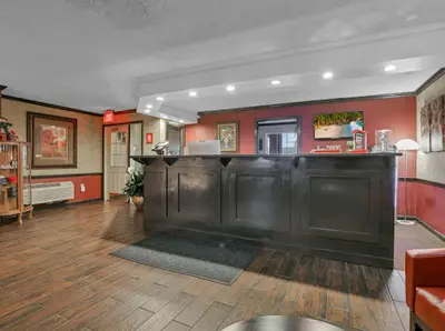 a bar in a living room with red walls at Red Roof Inn Uhrichsville in Uhrichsville