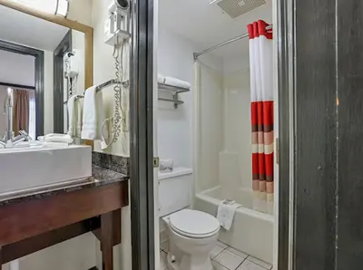 a bathroom with a toilet and a sink and a tub at Red Roof Inn Uhrichsville in Uhrichsville