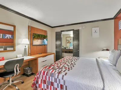 a hotel room with a bed and a desk and a computer at Red Roof Inn Uhrichsville in Uhrichsville