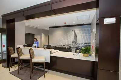 a woman standing at a counter in a office with a picture of a bridge at Staybridge Suites Miamisburg by IHG in Miamisburg