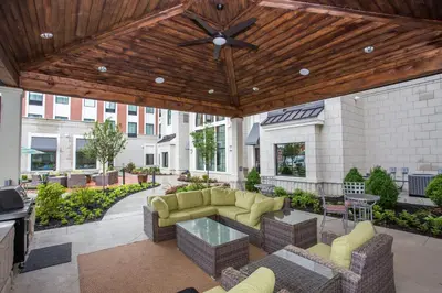 a covered patio with a couch and tables and chairs at Staybridge Suites Miamisburg by IHG in Miamisburg