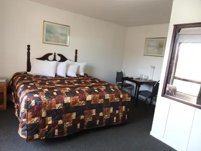 a bedroom with a bed and a table and a window at Liberty Motel in Liberty