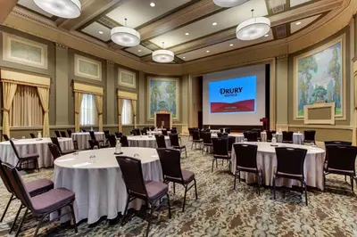 a conference room with tables and chairs and a screen at Drury Plaza Hotel Cleveland Downtown in Cleveland