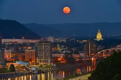 a full moon rising over a city at night at Holiday Inn Express Charleston-Civic Center by IHG in Charleston
