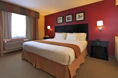a large bed in a hotel room with a red wall at Holiday Inn Express Hotel & Suites Defiance by IHG in Defiance