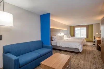 a hotel room with a bed and a blue couch at Holiday Inn Express Hotel & Suites Greenville by IHG in Greenville
