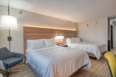 a hotel room with two beds and a chair at Holiday Inn Express Hotel & Suites Greenville by IHG in Greenville